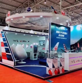 American Airlines exhibition stand with a circular overhead sign, tail-fin graphics and seating
